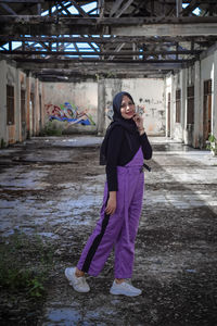 Full length portrait of woman standing against building