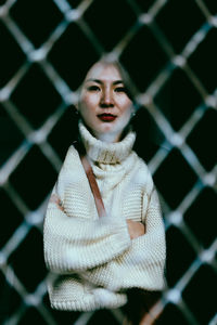 Portrait of woman standing against fence