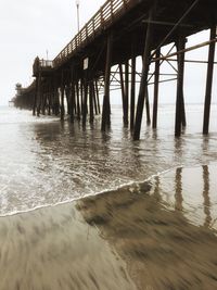 Silhouette pier on beach against sky