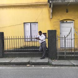 Side view of man standing on footpath by building