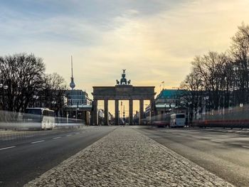 Road by buildings in city against sky