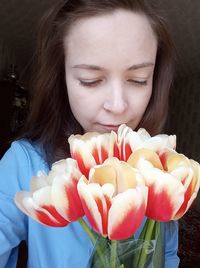 Close-up portrait of beautiful woman holding red flower