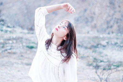 Portrait of young woman standing against sky