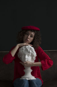 Girl looking away while sitting against black background