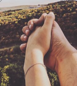 Cropped image of couple holding hands against railing