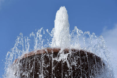 Water splashing from fountain against clear blue sky