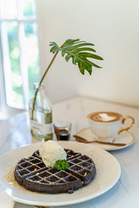 Chocolate waffle with vanilla icecream topping serves with hot coffee