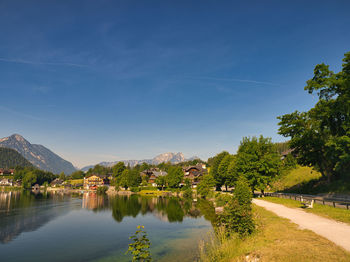 Scenic view of lake by trees against blue sky