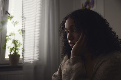 Pensive young woman sitting at home