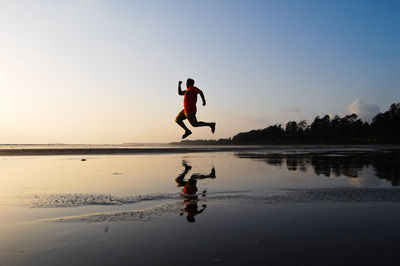 Side view of man jumping by sea