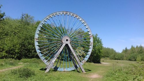 Ferris wheel on field against clear blue sky
