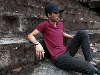 Thoughtful young man looking away while sitting on steps