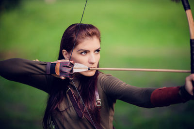 Beautiful woman holding bow and arrow standing outdoors