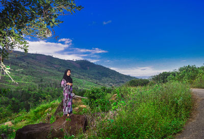 Woman wearing hijab standing on rock against mountains