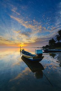 Boat moored on sea against sky during sunset