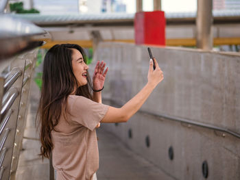 Young woman photographing with mobile phone while standing on bus