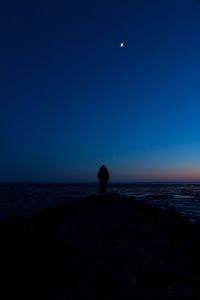 Silhouette man in sea against sky at night