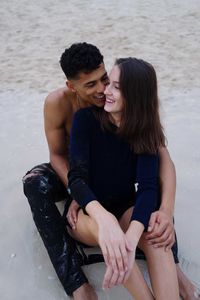 Portrait of young couple sitting at beach