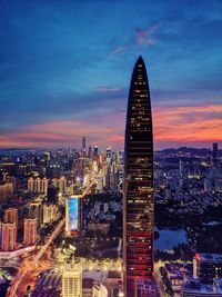 Illuminated buildings in city against sky during sunset