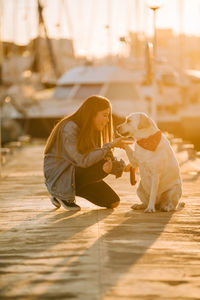 Woman with dog at harbor during sunset