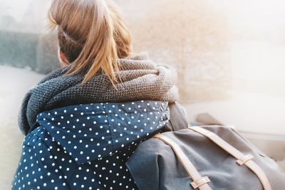 Rear view of backpack woman looking through window