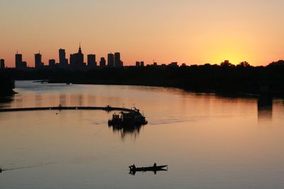 Silhouette boats in lake against clear sky during sunset