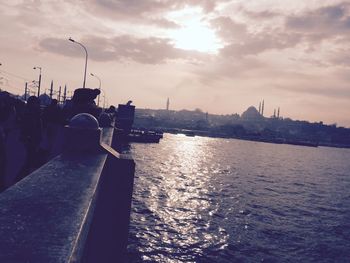 Boats in river against cloudy sky