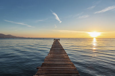 Wooden pier on sea against sky during sunset