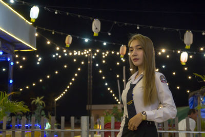 Portrait of student wearing uniform while standing in city at night