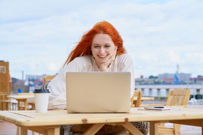 Young woman using laptop sitting at cafe