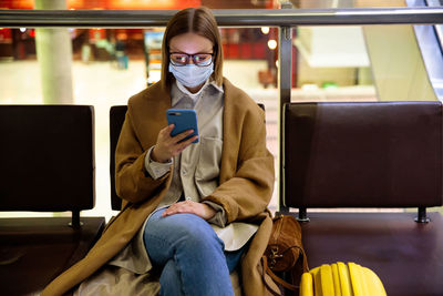 Woman using smart phone while sitting in waiting room