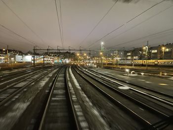 Railroad tracks in city against sky at night