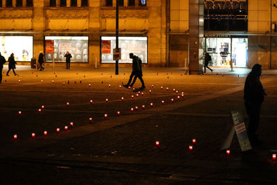 People walking on illuminated street at night