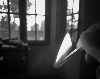 Close-up of hand holding lit matchstick at home