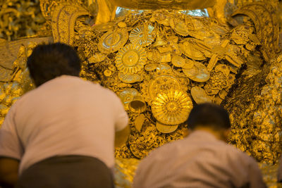 Rear view of men with religious gold offerings at temple