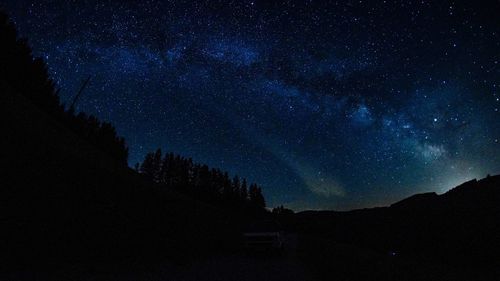 Silhouette mountain against star field at night