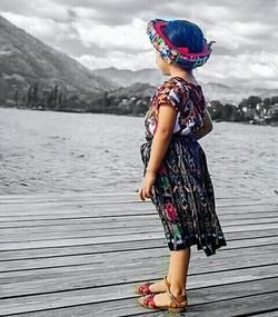 Boy standing by lake against sky