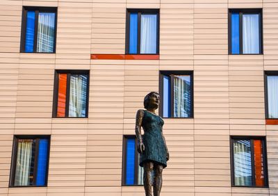 Statue of a woman standing against modern facade of building