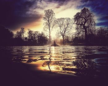 Silhouette trees by lake against sky during sunset