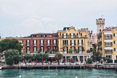 Buildings by river in city against sky