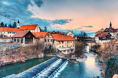 Houses by river against sky in city