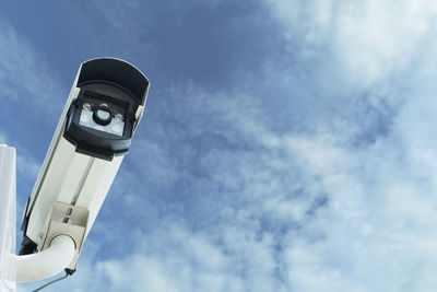 Low angle view of security camera against blue sky