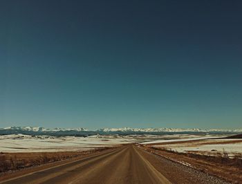 Road against clear blue sky