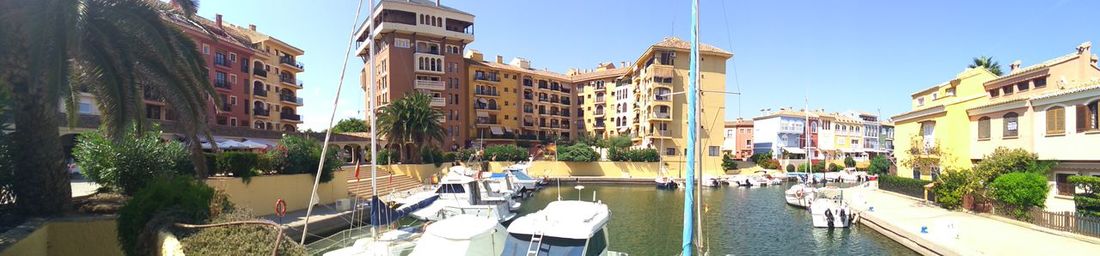 Boats moored on canal in city against clear sky