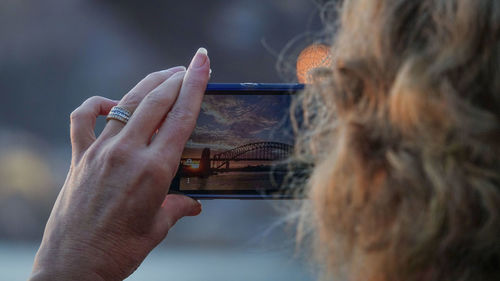 Close-up of woman photographing sydney harbour bridge with smart phone