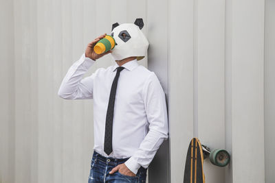 Businessman with panda bear mask drinking coffee