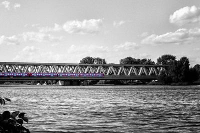 Bridge over river against cloudy sky