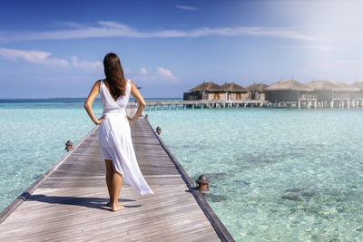 Portrait of young woman standing by sea against sky