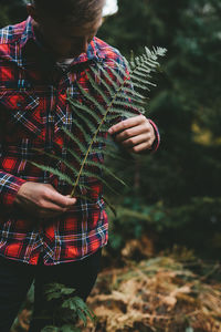 Midsection of man standing by tree in forest