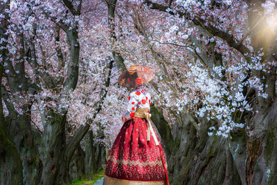 Woman standing by cherry blossom tree